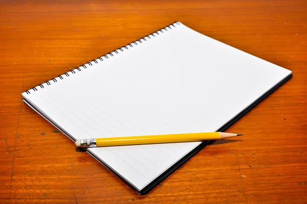 Cuaderno blanco en blanco con lápiz amarillo sobre fondo de madera — Foto de Stock