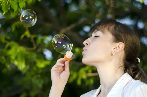 Young girl inflates soap bubbles — Stock Photo, Image