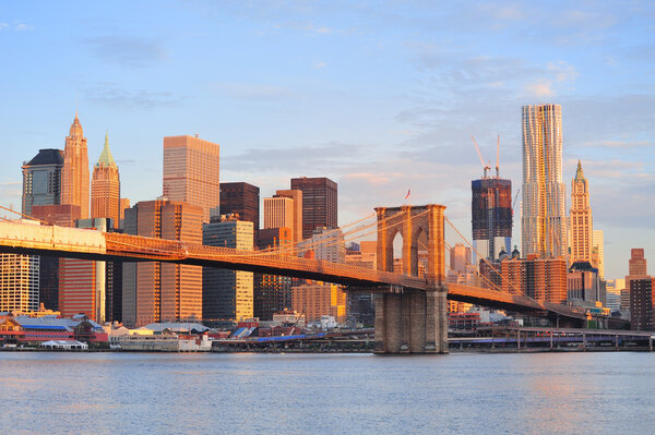 Brooklyn Bridge with lower Manhattan skyline in the morning with colorful cloud over East River in New York City