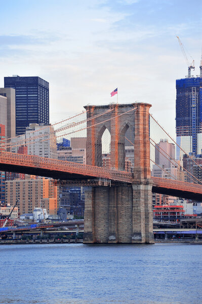 Brooklyn Bridge with lower Manhattan skyline in the morning with colorful cloud over East River in New York City