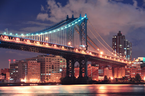 Manhattan Bridge closeup over East River at night in New York City Manhattan with lights and reflections.