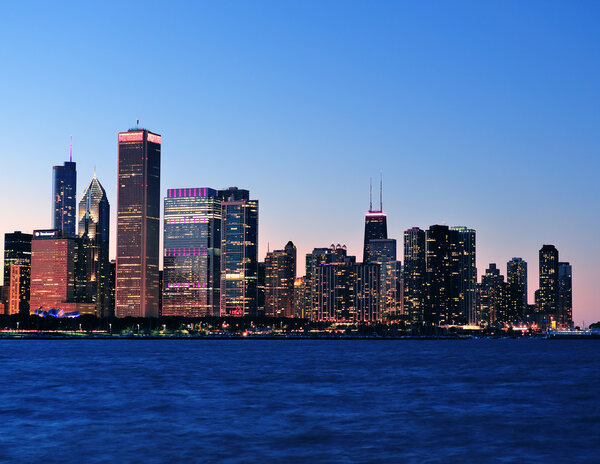 Chicago city downtown urban skyline at dusk with skyscrapers over Lake Michigan with clear blue sky.