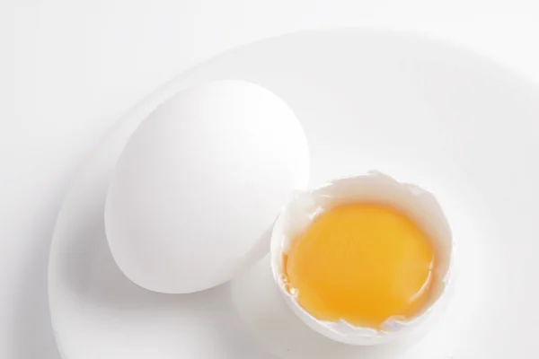 Яєчний жовток в шкаралупі на білій тарілці . — стокове фото