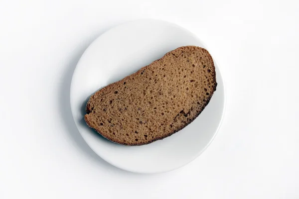 Fetta di pane su un piatto bianco su fondo bianco . — Foto Stock