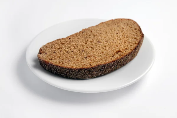 Fetta di pane su un piatto bianco su fondo bianco . — Foto Stock