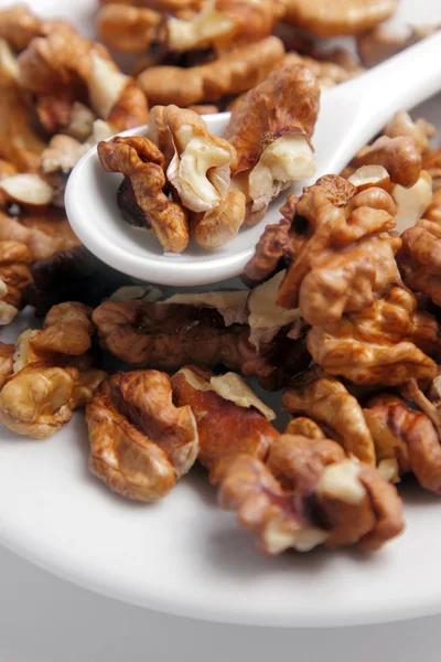 Stock image Shelled nuts on a white plate with a spoon.