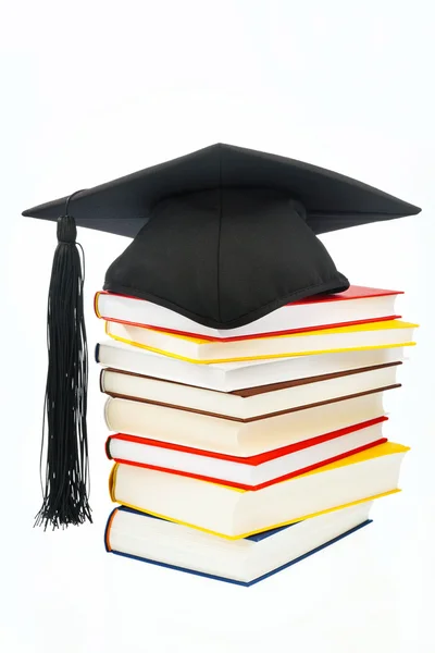 A mortarboard on a book stack on white background — Stock Photo, Image