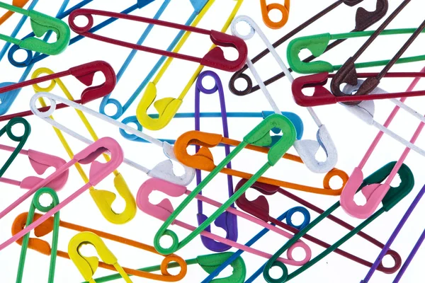 Lots of colorful safety pin lying on a white background — Stock Photo, Image