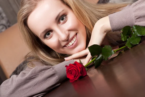 Vackra leende blond flicka med en röd ros — Stockfoto