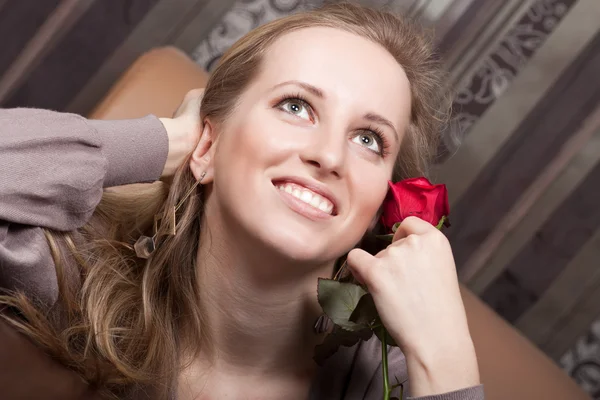 Hermosa chica rubia sonriente con una rosa roja — Foto de Stock