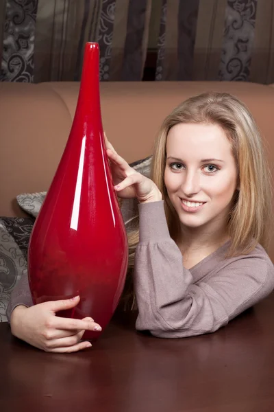 Досить усміхнена блондинка з великою червоною вазою — стокове фото