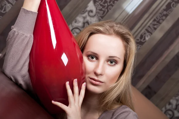 Pretty young blond girl with a big red vase — Stock Photo, Image