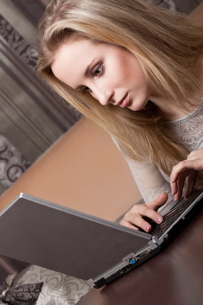 Hermosa chica rubia está trabajando en un ordenador portátil —  Fotos de Stock