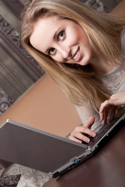 Chica rubia alegre está trabajando en un ordenador portátil —  Fotos de Stock