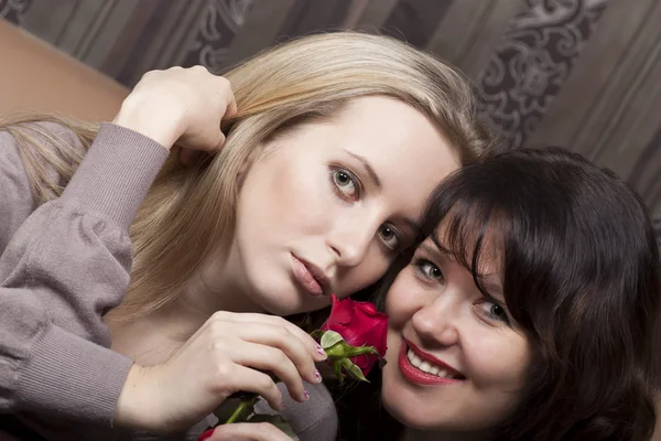 两个华丽微笑女孩与一朵红玫瑰 — 图库照片