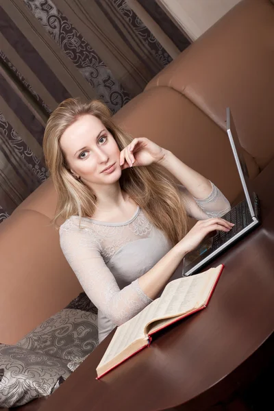 Sexy chica rubia joven con un ordenador portátil y libro — Foto de Stock