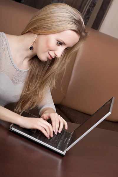 Chica rubia alegre está trabajando en un ordenador portátil — Foto de Stock
