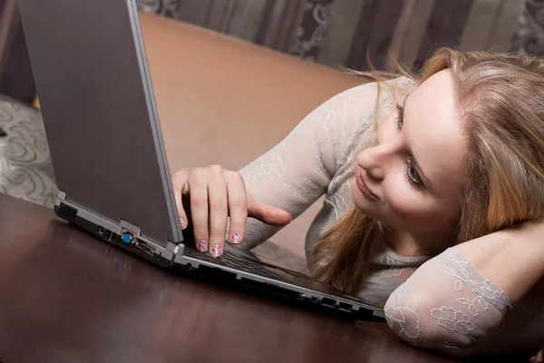 Atractiva chica rubia está trabajando en un ordenador portátil — Foto de Stock