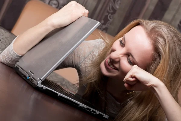 Smiling blond girl is punching a laptop — Stock Photo, Image