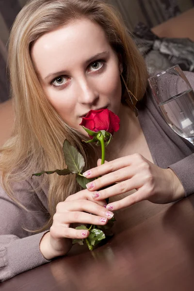 Sensuele blond meisje met een rode roos in haar handen — Stockfoto