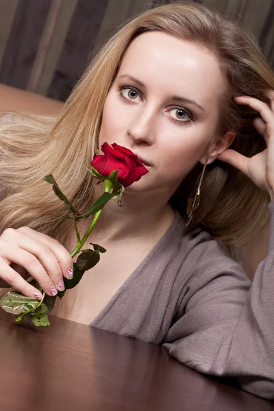 Hermosa joven rubia con una rosa roja — Foto de Stock