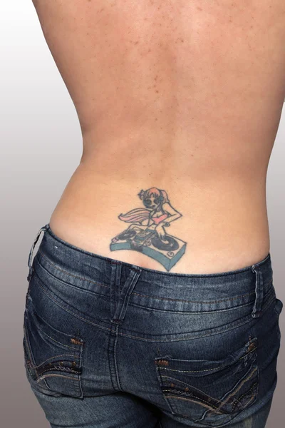 Tatuagem de DJ feminina em uma parte inferior das costas feminina — Fotografia de Stock