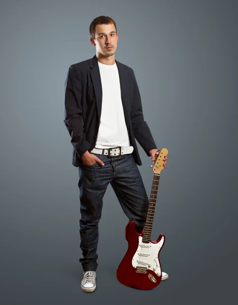 Stilvoller Mann mit Gitarre blickt in die Kamera — Stockfoto