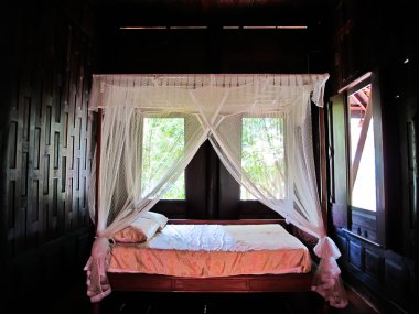 Bed and mattress in a wooden Thai house clipart