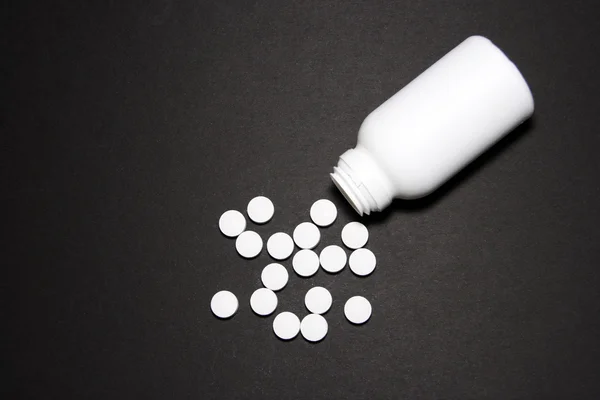 Белые таблетки на черном фоне — стоковое фото