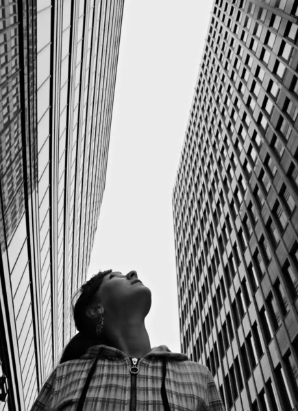 stock image Girl looks upwards at high-rise buildings