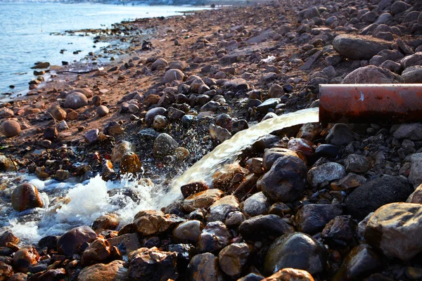 Flusso che scorre da un tubo su rocce in primavera — Foto Stock