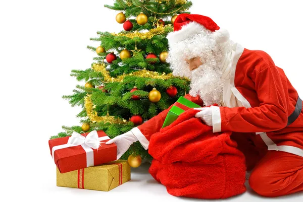 Санта кладет подарочные коробки под елку — стоковое фото