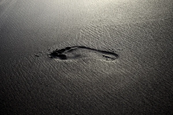 stock image Female footprint on a black volcanic sand