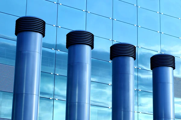Cuatro conos de aire acondicionado frente a una moderna fachada de cristal Imagen De Stock