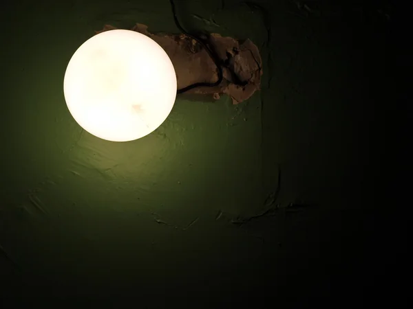 Круглая лампа на зеленой стене — стоковое фото