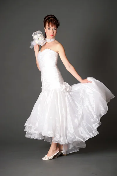 Giovane donna in abito sposa con bouquet in studio — Foto Stock