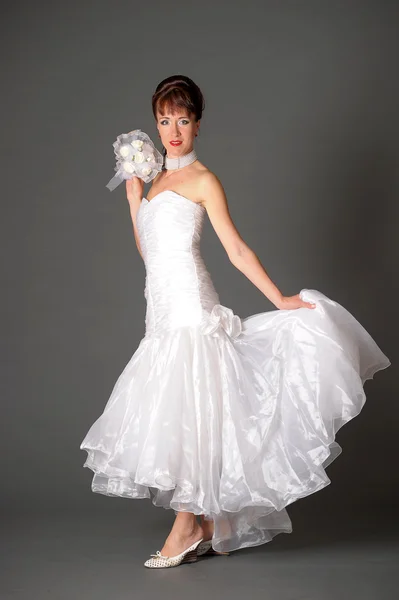 Ung kvinna i klänning bruden med bukett i studio — Stockfoto