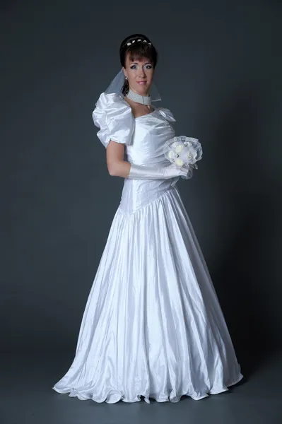 Jeune femme en robe mariée avec bouquet en studio — Photo