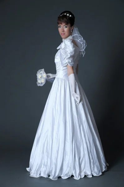Νεαρή γυναίκα στο φόρεμα νύφη με ανθοδέσμη στο στούντιο — Φωτογραφία Αρχείου