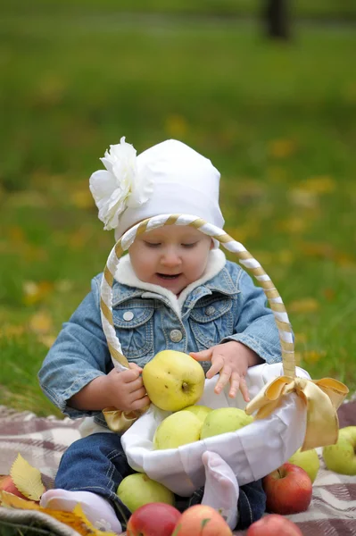 Menina senta-se com uma cesta de maçãs — Fotografia de Stock