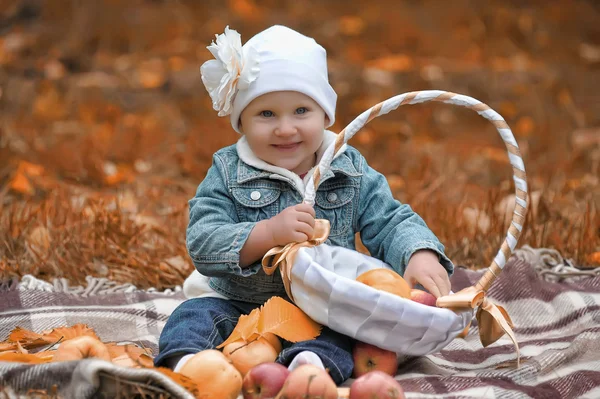 Petite fille assise avec un panier de pommes — Photo
