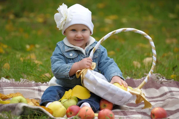 Malá holka sedí s košem jablek — Stock fotografie