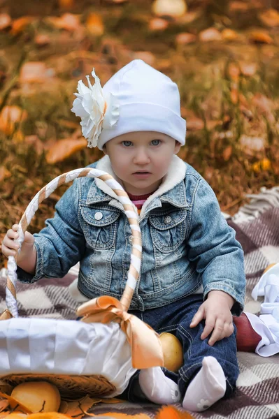 Klein meisje zit met een mandje van appels — Stockfoto