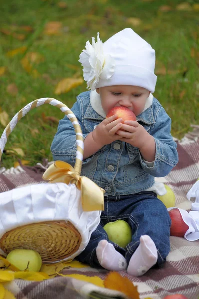 Menina senta-se com uma cesta de maçãs — Fotografia de Stock