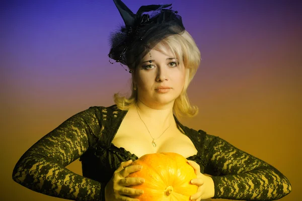 Retrato de uma jovem bruxa segurando uma abóbora — Fotografia de Stock