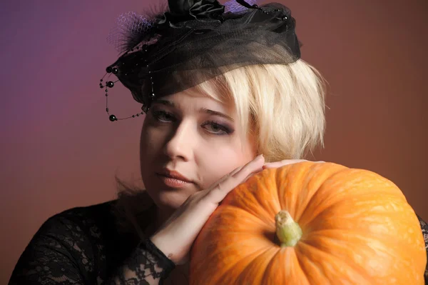 Retrato de uma jovem bruxa segurando uma abóbora — Fotografia de Stock