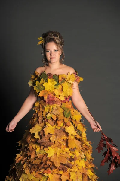 The woman in a dress from autumn leaves — Stock Photo, Image