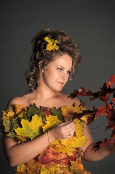 The woman in a dress from autumn leaves — Stockfoto