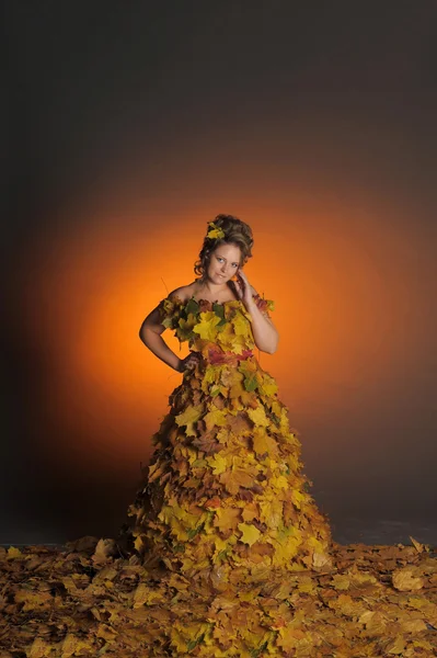 A mulher em um vestido de folhas de outono — Fotografia de Stock