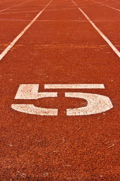 Número cinco al inicio de una pista de atletismo — Foto de Stock